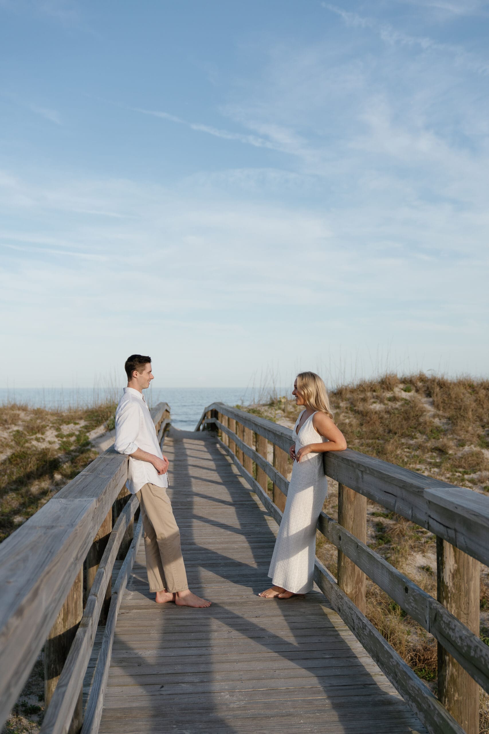 couple leaning on boardwalk looking at each other on the beach Shelby Ann Photos