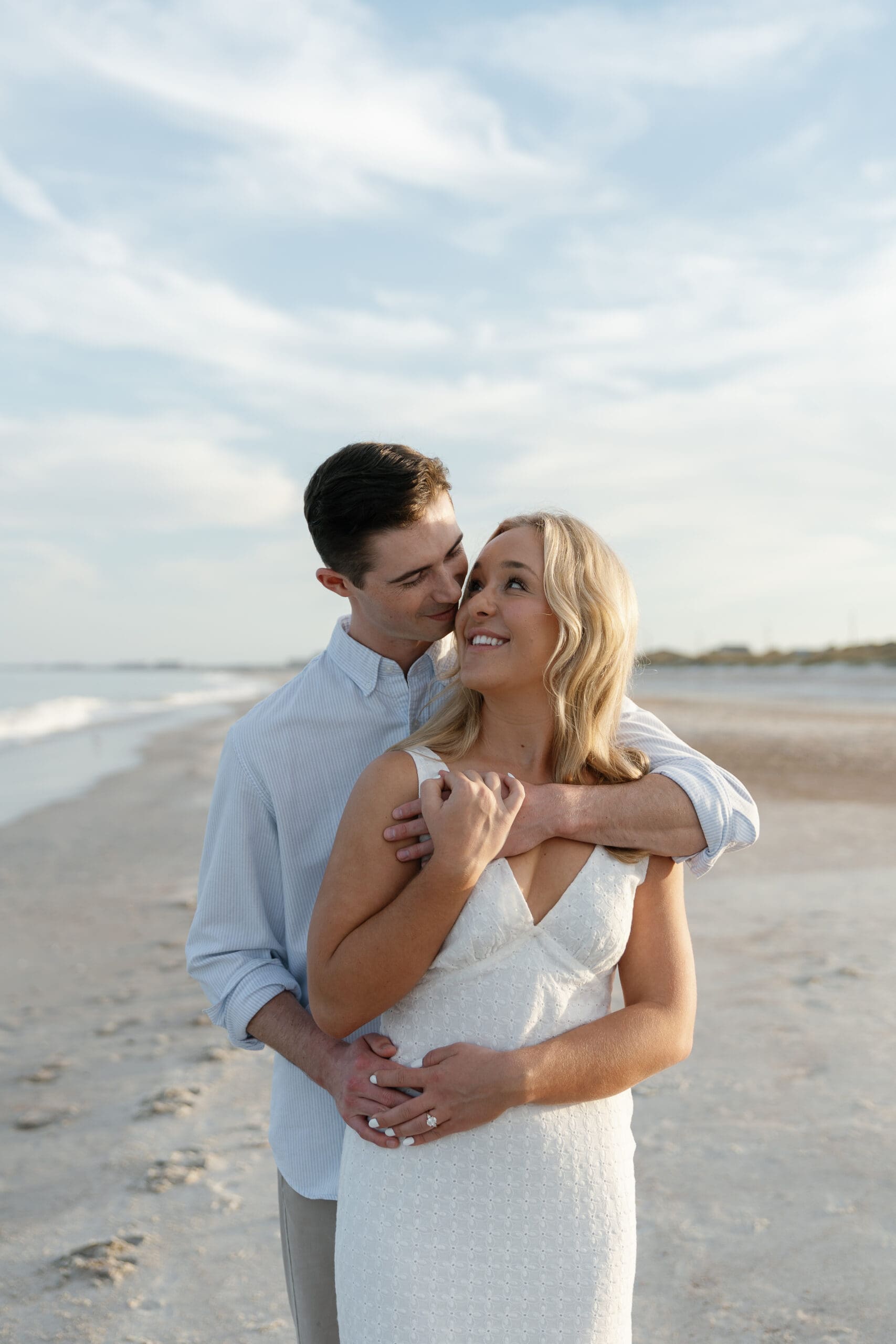 Groom wrapping up bride in hug from behind and smiling at each other