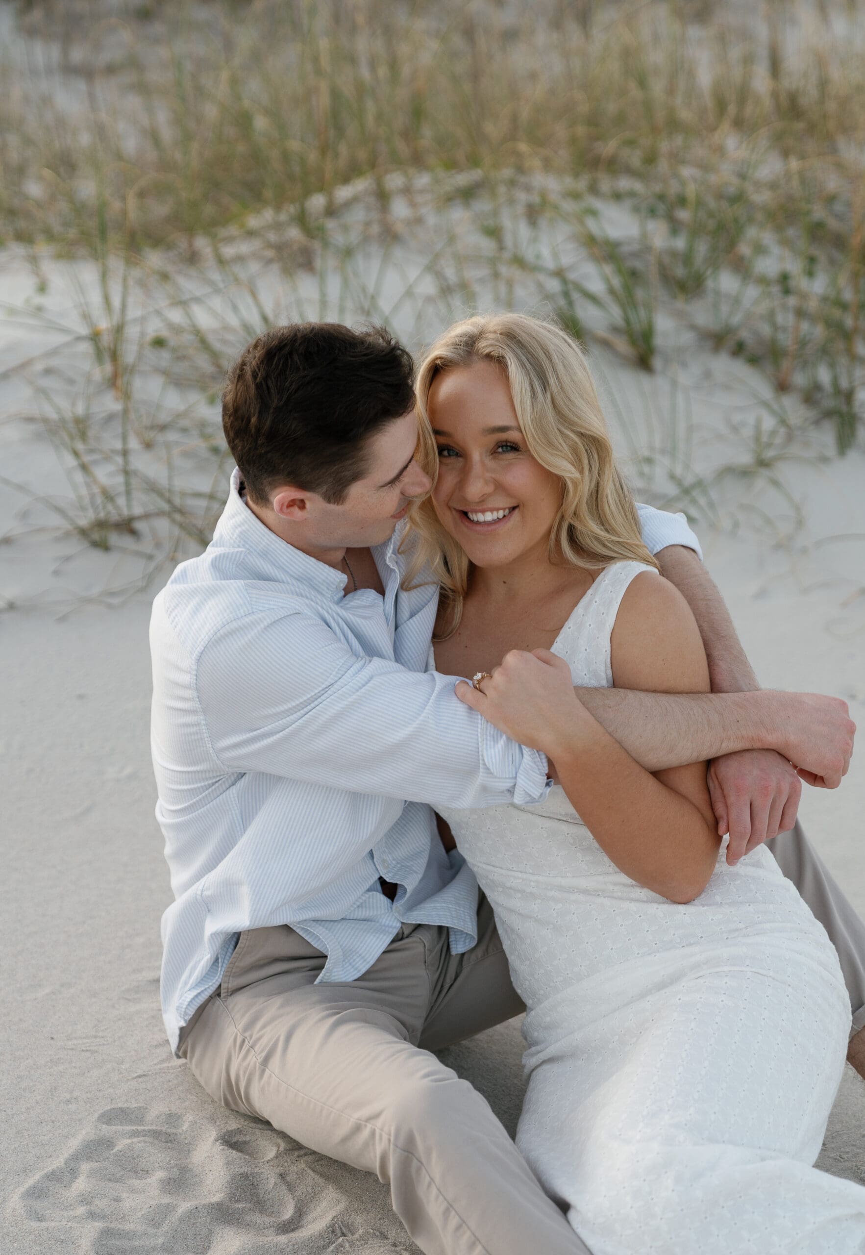 Couple sitting in each others arms, bride smiling at camera