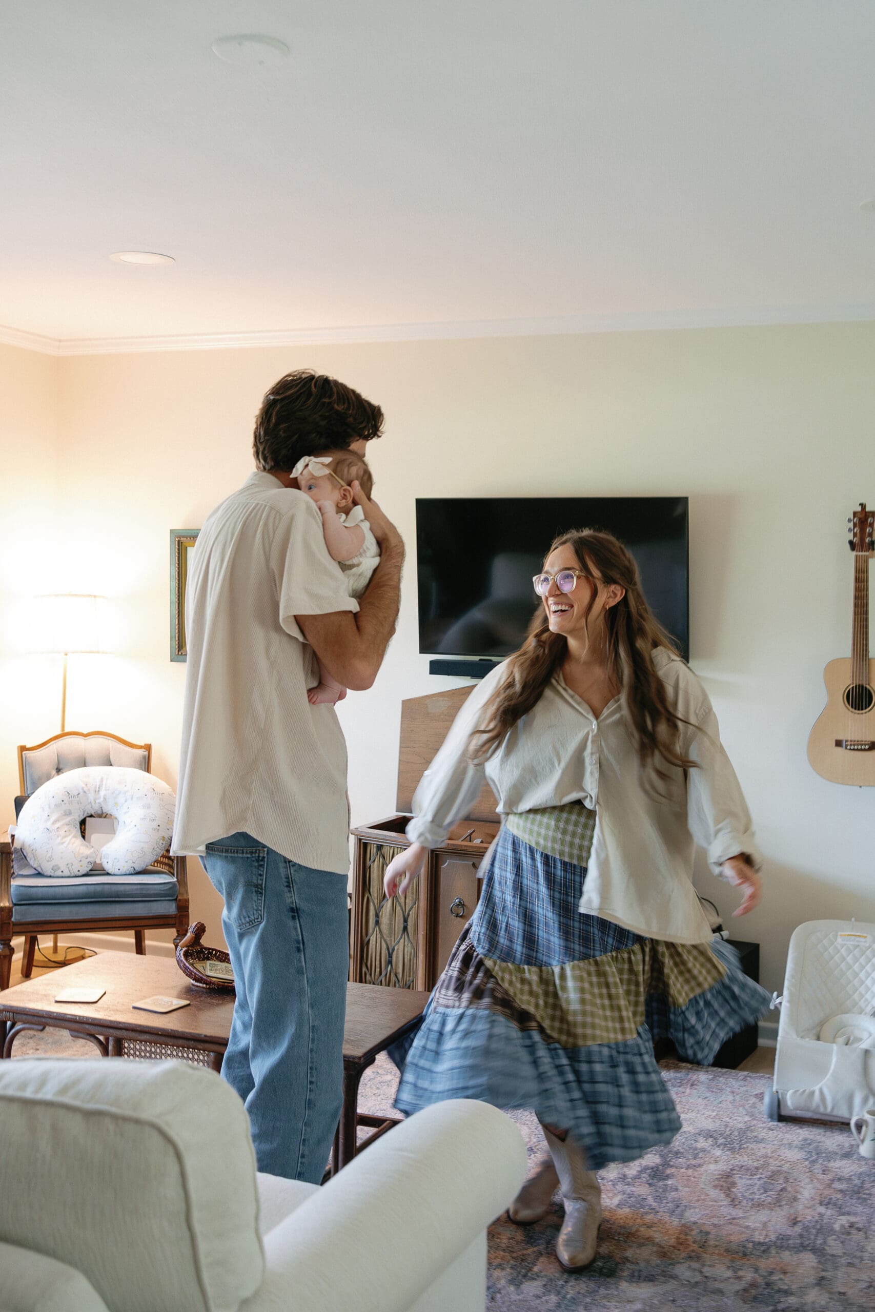 Dad holding baby and mom dancing at home