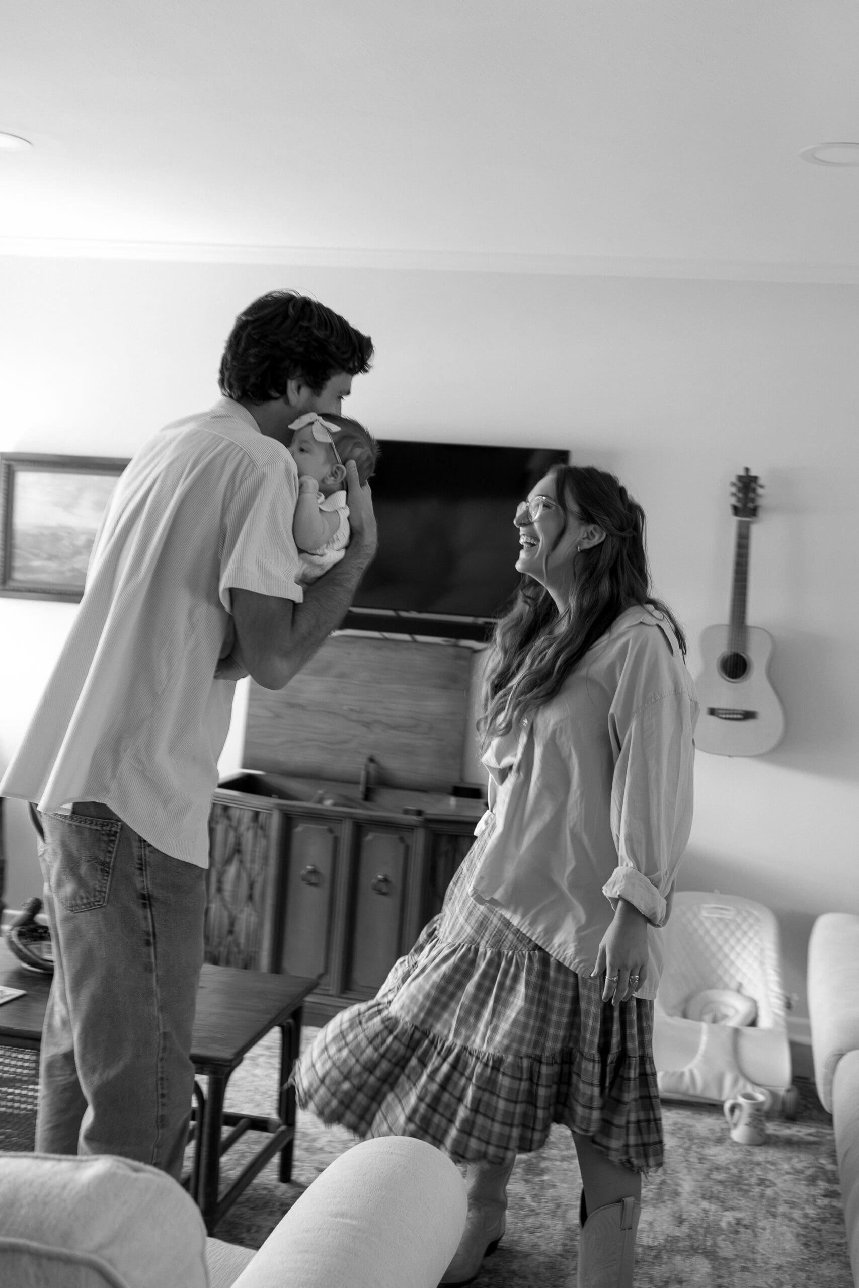 Couple laughing at each other with baby at home