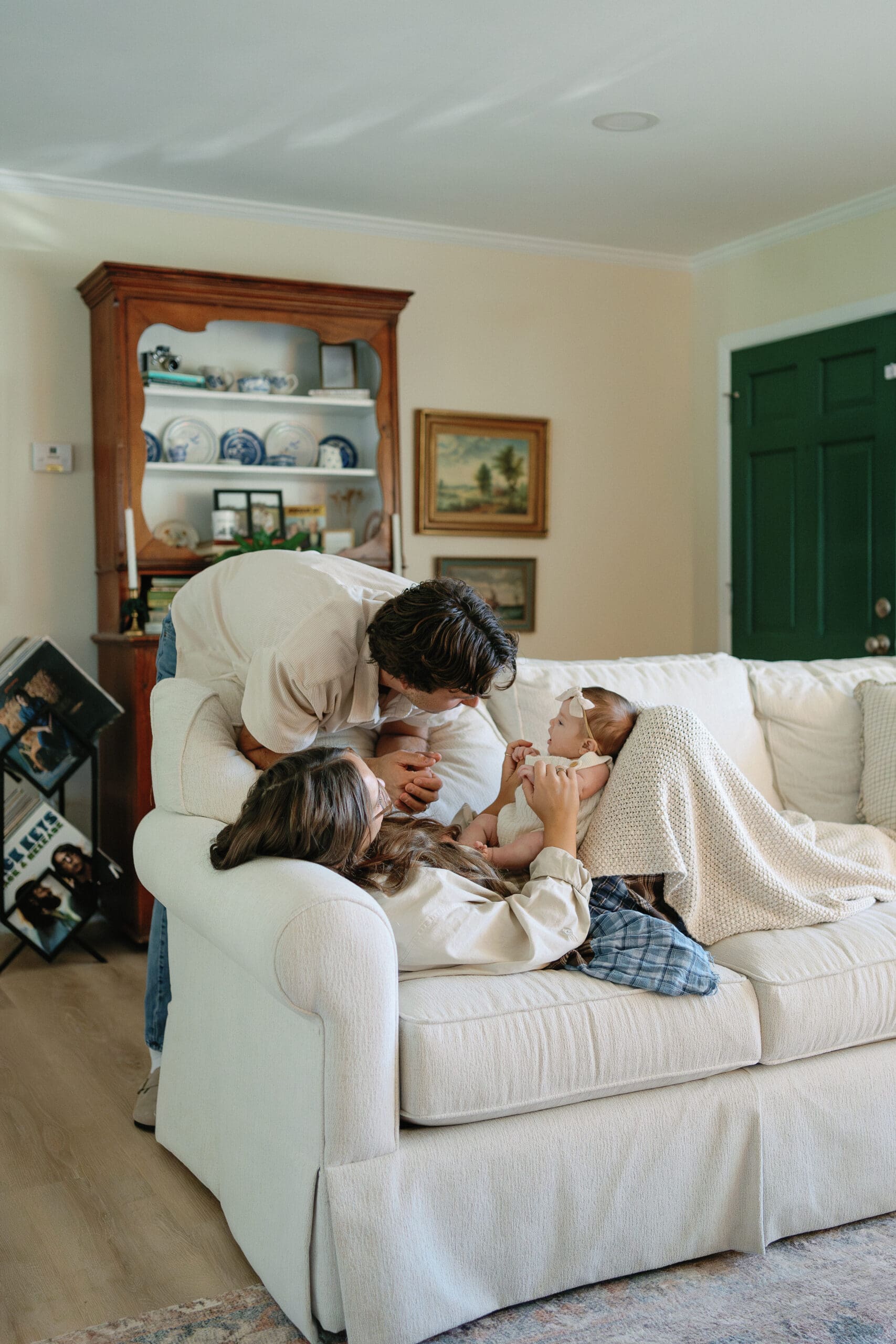 Mom laying on couch with baby and dad looking down