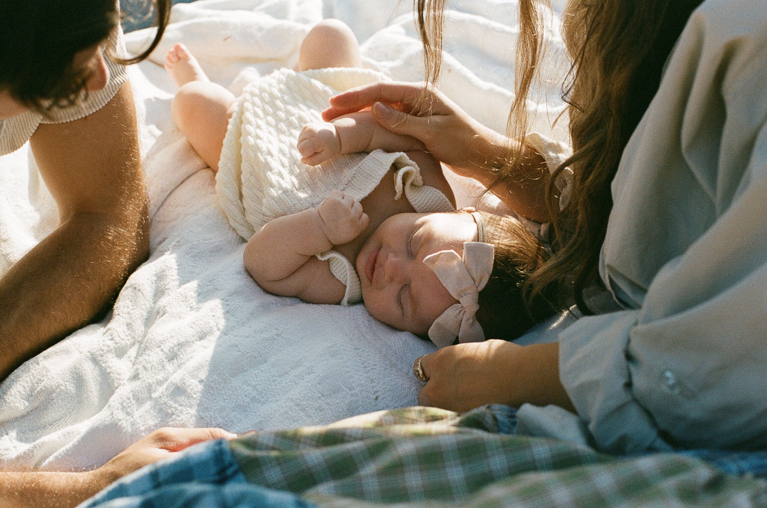 Couple watching baby sleep on blanket outdoors