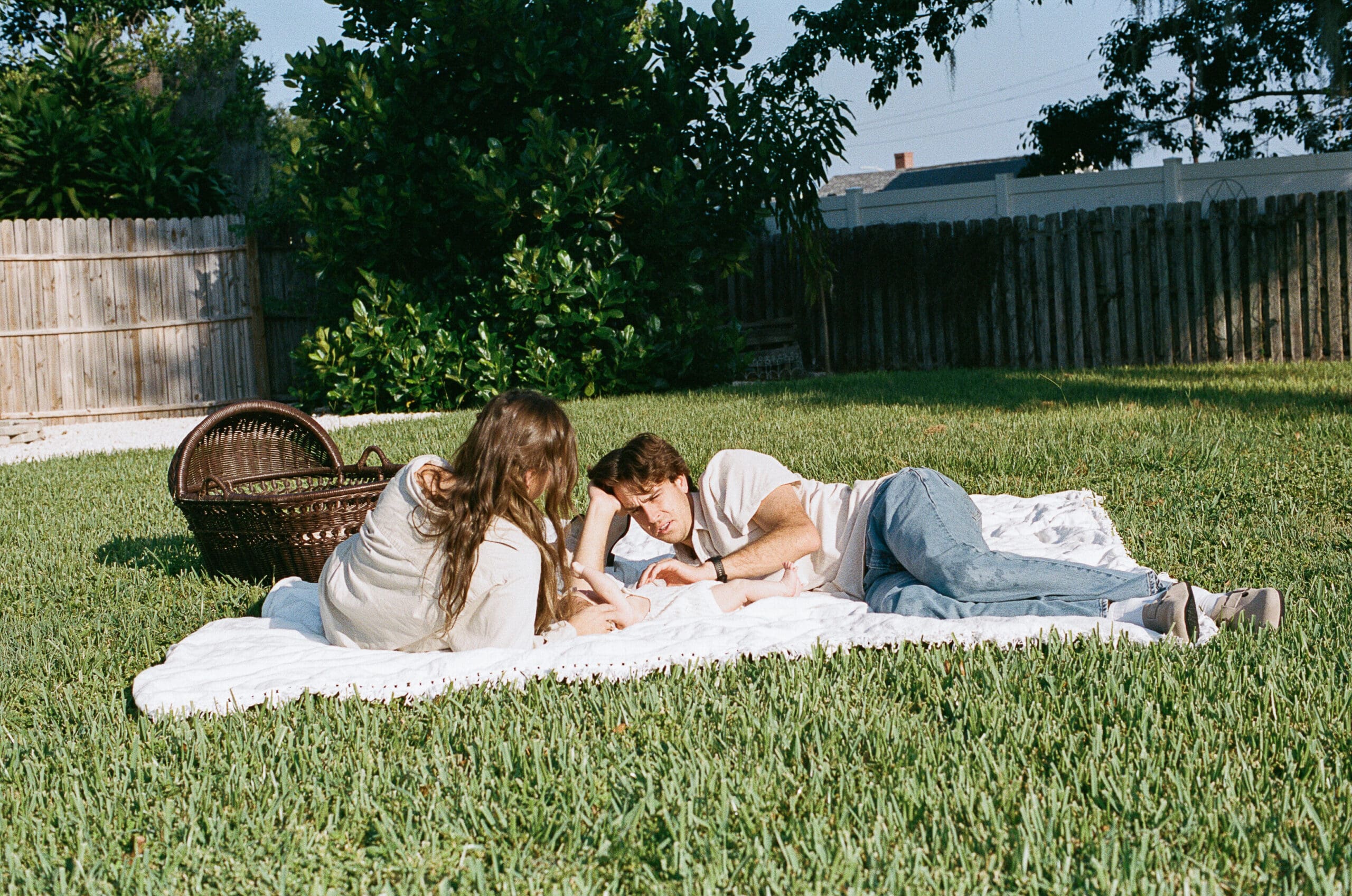 Couple laying down on blanket with their baby