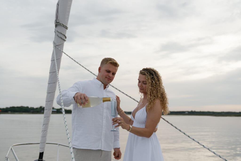 Couple pouring champagne on the bow of a sailboat in Amelia Island, Florida taken by Shelby Ann Photos