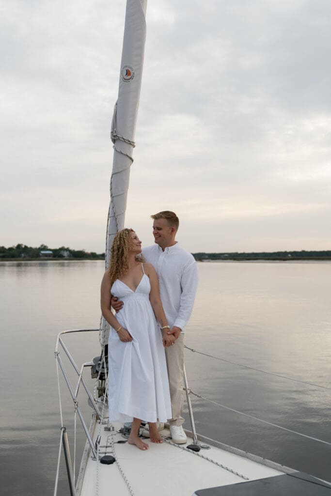 Couple posing on sailboat for engagement photos by Shelby Ann Photos