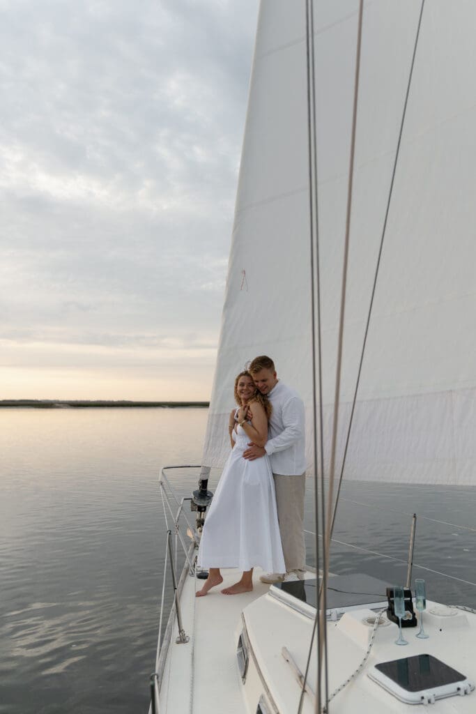 Couple wrapped up in each others arms while sailing on a boat by Shelby Ann Photos