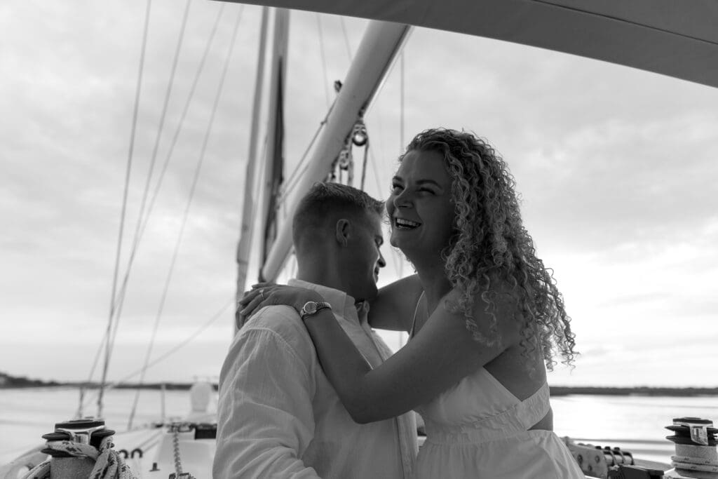 Couple leaning into each other and laughing on a boat taken by Shelby Ann Photos