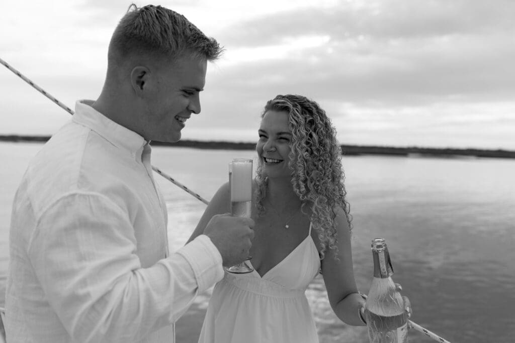 Couple laughing together holding a bottle of wine for engagement photos by Shelby Ann Photos