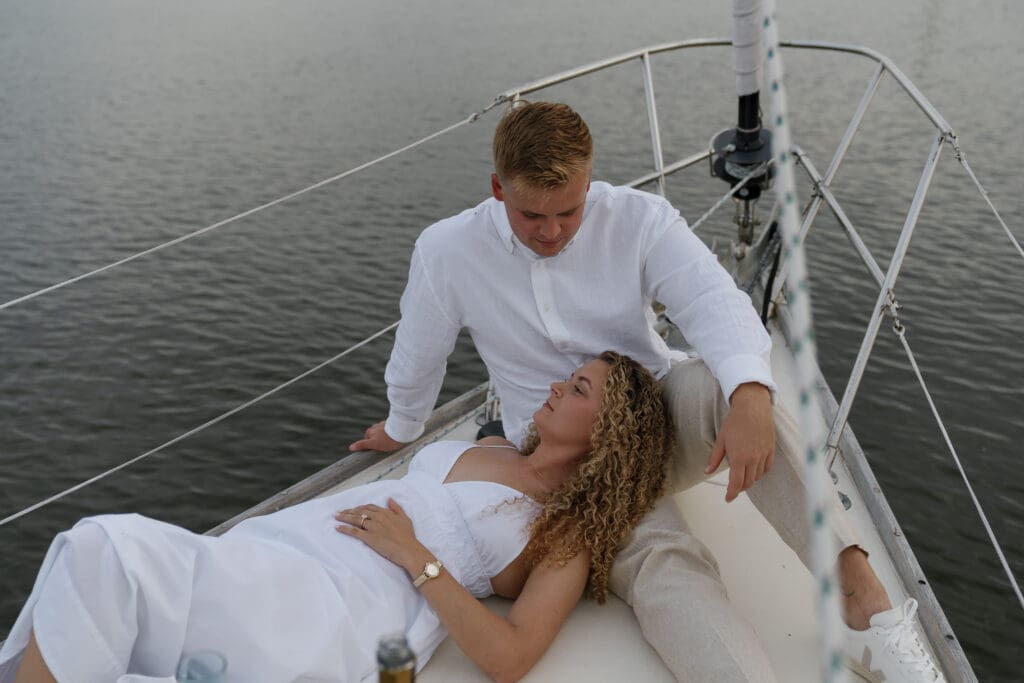 Girl lying on her fiance's lap on a sailboat for engagement photos by Shelby Ann Photos