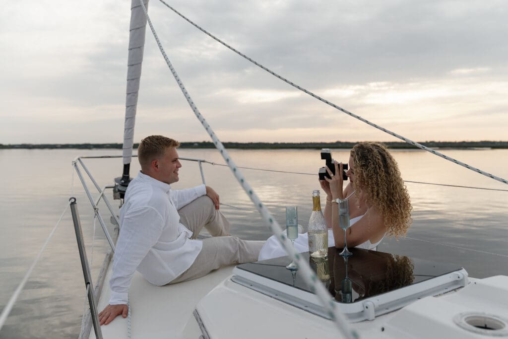Couple sitting on sailboat taking pictures of each other by Shelby Ann Photos
